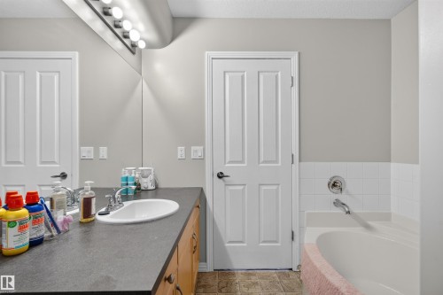 Bathroom featuring a built-in vanity with an integrated sink, surface-mounted lighting fixture, and a built-in tub with tile surround - 4471 Mccrae Avenue Nw, Edmonton, AB - Indoor Photo Showing Bathroom