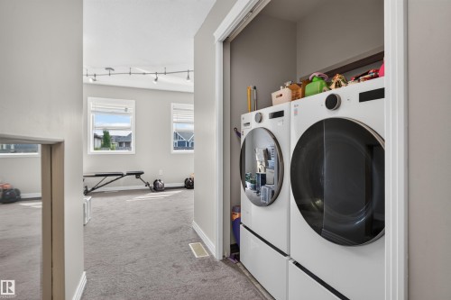 Front-loading washer and dryer set, track lighting, and two windows with blinds - 4471 Mccrae Avenue Nw, Edmonton, AB - Indoor Photo Showing Laundry Room