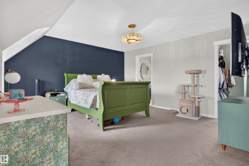 Carpeted room featuring a ceiling-mounted light fixture, an accent wall, and a built-in closet with a doorway - 4471 Mccrae Avenue Nw, Edmonton, AB - Indoor