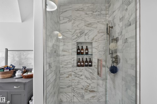 Glass-enclosed shower with marble-style tile surround, recessed shelving, and a mosaic tile floor - 4471 Mccrae Avenue Nw, Edmonton, AB - Indoor Photo Showing Bathroom
