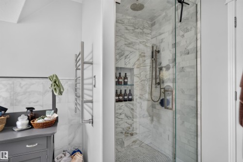 Glass-enclosed shower with marble-style tile walls, rain shower head, and built-in shelving - 4471 Mccrae Avenue Nw, Edmonton, AB - Indoor Photo Showing Bathroom