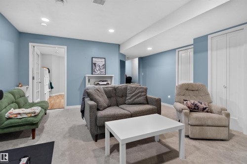 Recessed lighting, light blue wall paint, French doors, wood-finish flooring, and white bi-fold doors - 4471 Mccrae Avenue Nw, Edmonton, AB - Indoor Photo Showing Living Room