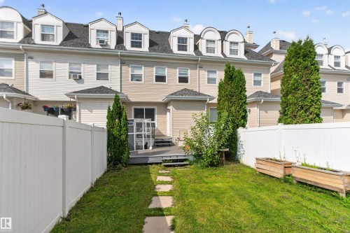 Private backyard featuring a paved stone path, white vinyl fencing, and a raised wooden deck with steps - 4471 Mccrae Avenue Nw, Edmonton, AB - Outdoor