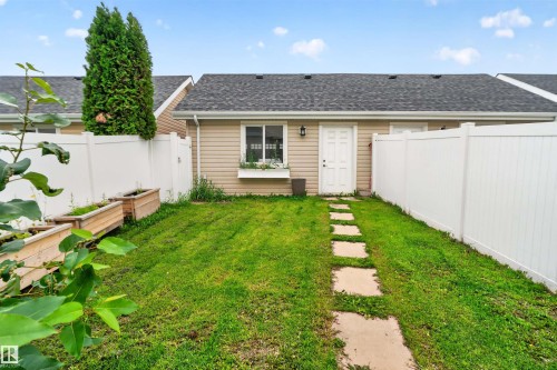 Backyard featuring a privacy fence, manicured lawn, stone pathway, and raised garden beds - 4471 Mccrae Avenue Nw, Edmonton, AB - Outdoor