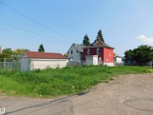 Expansive land parcel featuring a detached shed with a red shingle roof, chain-link perimeter fencing, and established ground cover - 9352 107A Avenue Nw, Edmonton, AB 