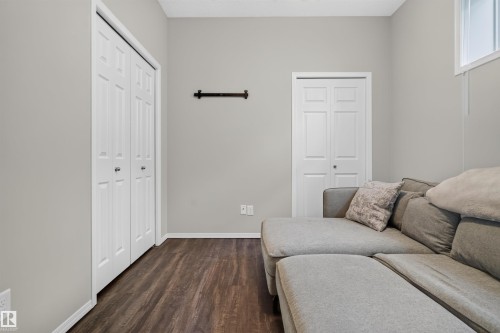 Wood-finish flooring, light grey wall paint, two white bi-fold doors, white trim, and a high-set window - #34 6520 2 Av Sw, Edmonton, AB - Indoor