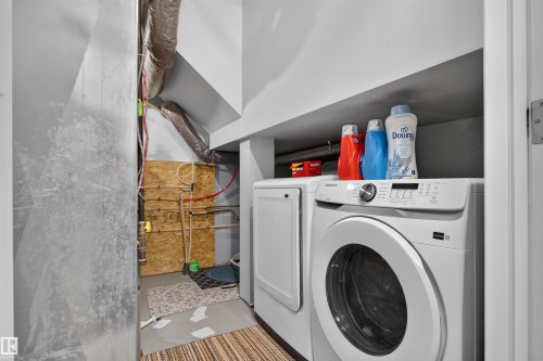 Laundry area featuring a stackable washer and dryer, adjacent utility access, and overhead shelving - #34 6520 2 Av Sw, Edmonton, AB - Indoor Photo Showing Laundry Room
