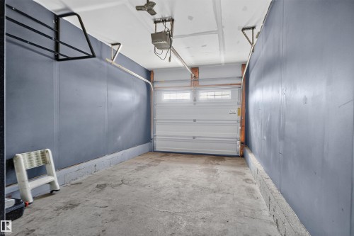 Single-car garage with concrete flooring, automatic garage door opener, and a ceiling fan - #34 6520 2 Av Sw, Edmonton, AB - Indoor Photo Showing Garage