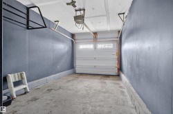 Single-car garage with concrete flooring, automatic garage door opener, and a ceiling fan - 