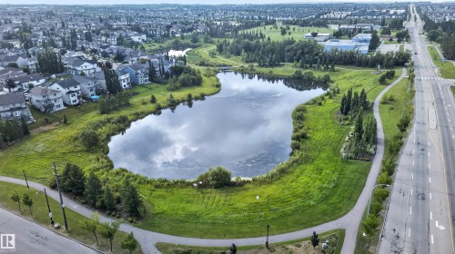 Residential area with a central lake feature, surrounded by natural landscaping and paved pathways - #34 6520 2 Av Sw, Edmonton, AB - Outdoor With View