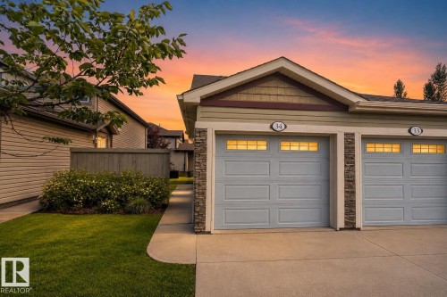 Attached two-car garage with stone accents, horizontal siding, and a gabled roofline - #34 6520 2 Av Sw, Edmonton, AB - Outdoor