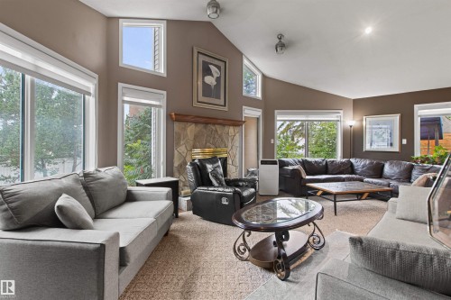 Vaulted ceiling living space featuring a stone-clad fireplace with a wood mantel, multiple windows, and recessed lighting - 11139 157 Avenue Nw, Edmonton, AB - Indoor Photo Showing Living Room With Fireplace