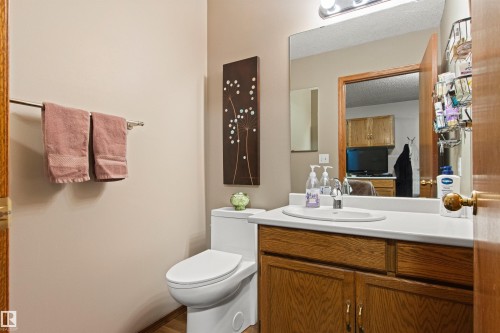Wood-finish flooring with a white toilet, wood vanity, white countertop, and integrated sink - 11139 157 Avenue Nw, Edmonton, AB - Indoor Photo Showing Bathroom