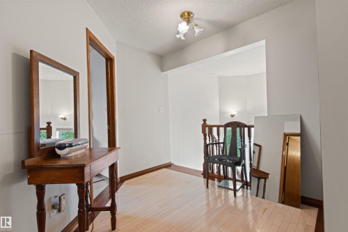 Wood-finish flooring with a wood railing and trim accents - 11139 157 Avenue Nw, Edmonton, AB - Indoor Photo Showing Other Room