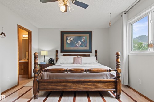 Wood-finish flooring with accent strips, ceiling fan with integrated lighting, and a single window with white trim - 11139 157 Avenue Nw, Edmonton, AB - Indoor Photo Showing Bedroom