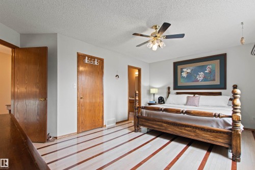 Light wood-finish flooring with accent strips, ceiling fan with integrated lighting, wood-paneled doors, and light gray wall paint - 11139 157 Avenue Nw, Edmonton, AB - Indoor Photo Showing Bedroom