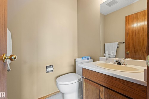 Wood-finish vanity with an integrated sink, polished chrome faucet, and full-width wall mirror - 11139 157 Avenue Nw, Edmonton, AB - Indoor Photo Showing Bathroom