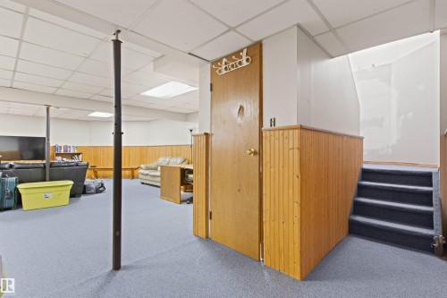Carpeted flooring, wood-paneled walls, a drop ceiling, and a wooden door - 11139 157 Avenue Nw, Edmonton, AB - Indoor