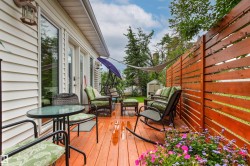 Expansive wood deck with a privacy fence, multiple outdoor seating areas, and a built-in garden bed - 