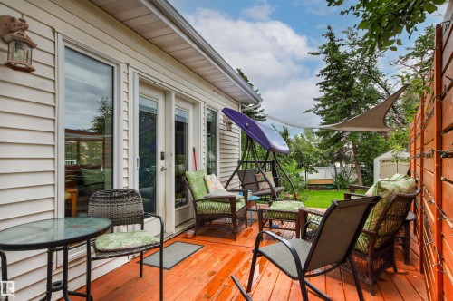 Expansive wood-finish deck with multiple seating areas, a privacy fence, and direct access to the interior through a glass-paneled door - 11139 157 Avenue Nw, Edmonton, AB - Outdoor With Deck Patio Veranda With Exterior