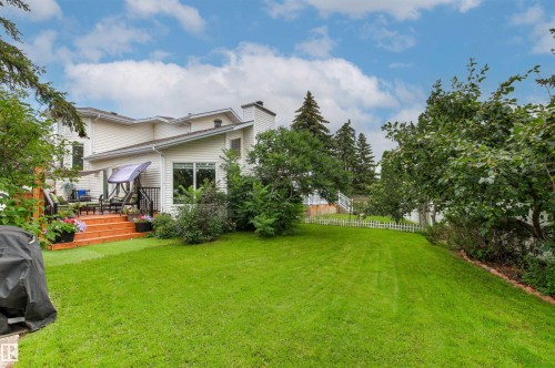 Expansive backyard featuring a manicured lawn, established landscaping, and a multi-level wood deck with black metal railings - 11139 157 Avenue Nw, Edmonton, AB - Outdoor