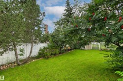 Manicured lawn with mature trees and a white chain-link fence - 