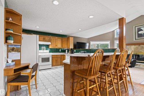 Kitchen featuring wood cabinetry, white appliances, and a tiled backsplash - 11139 157 Avenue Nw, Edmonton, AB - Indoor Photo Showing Other Room