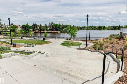 Concrete pathways and steps with black handrails, green spaces with mature trees, and a visible body of water - 11139 157 Avenue Nw, Edmonton, AB - Outdoor With Body Of Water With View