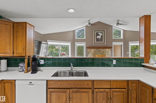 Kitchen featuring wood-finish cabinetry, white countertops, a stainless steel sink, and a built-in dishwasher - 11139 157 Avenue Nw, Edmonton, AB - Indoor Photo Showing Kitchen With Double Sink