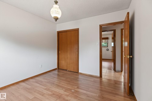 Hardwood-finish flooring, built-in closet with wood doors, and a decorative ceiling light fixture - 8411 136 Avenue Nw, Edmonton, AB - Indoor Photo Showing Other Room
