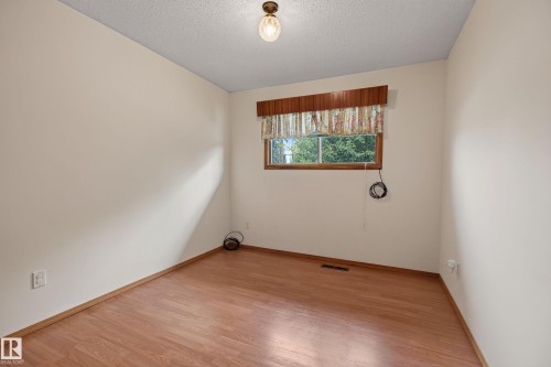 Wood-finish flooring with light-colored walls and a window with wood trim - 8411 136 Avenue Nw, Edmonton, AB - Indoor Photo Showing Other Room