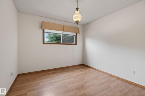 Wood-finish flooring, white painted walls, and a window with a wood frame - 8411 136 Avenue Nw, Edmonton, AB - Indoor Photo Showing Other Room
