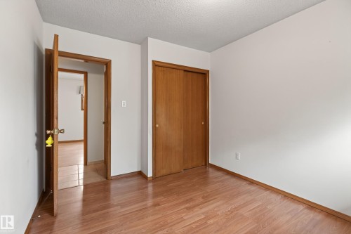 Wood-finish flooring, white painted walls, and a sliding door closet - 8411 136 Avenue Nw, Edmonton, AB - Indoor Photo Showing Other Room