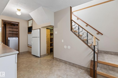 Tile flooring, wood tread staircase, decorative metal stair railing, built-in shelving, counter space with cabinetry - 8411 136 Avenue Nw, Edmonton, AB - Indoor Photo Showing Other Room