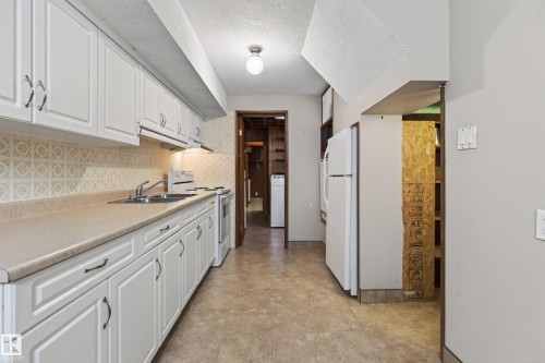 White cabinetry, light-toned countertops, and mosaic-patterned tile backsplash - 8411 136 Avenue Nw, Edmonton, AB - Indoor Photo Showing Kitchen With Double Sink