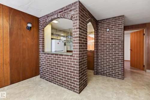 Brick partition wall with archway, wood paneling, and tile flooring - 8411 136 Avenue Nw, Edmonton, AB -  Photo Showing Other Room