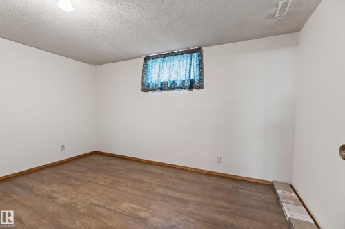 Wood-finish flooring, white walls, and a window with curtain - 8411 136 Avenue Nw, Edmonton, AB - Indoor Photo Showing Other Room