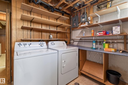 Dedicated laundry area featuring a washer and dryer, wood-paneling, open shelving, and a built-in counter - 8411 136 Avenue Nw, Edmonton, AB - Indoor Photo Showing Laundry Room