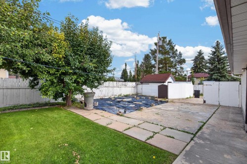 Expansive grass lawn, concrete patio, mature trees, white privacy fencing, and a detached shed - 8411 136 Avenue Nw, Edmonton, AB - Outdoor