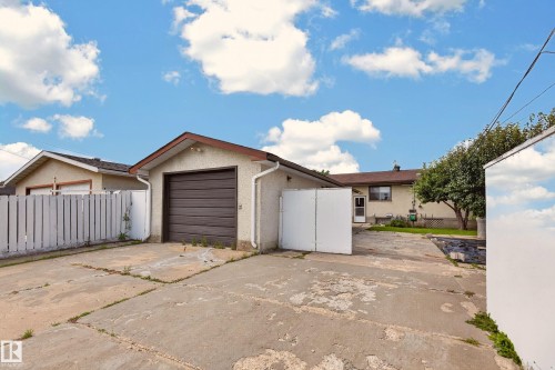 Detached garage with a brown sectional door, stucco exterior, and a white downspout - 8411 136 Avenue Nw, Edmonton, AB - Outdoor