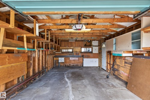 Attached garage with exposed wood framing, concrete flooring, and built-in shelving units - 8411 136 Avenue Nw, Edmonton, AB - Indoor Photo Showing Garage
