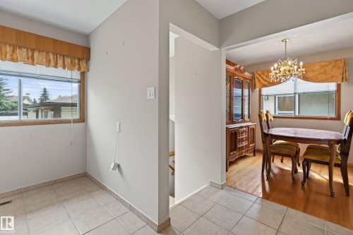 Tile flooring, wood-finish window frame, wood-finish flooring, and a chandelier lighting fixture - 8411 136 Avenue Nw, Edmonton, AB - Indoor