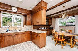 Kitchen and dining area featuring wood-finish cabinetry, tile countertops, and a window above the sink - 