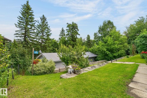 Expansive green lawn with established shrubbery, concrete retaining wall, and mature trees - 351 Smith Crescent, Rural Parkland County, AB - Outdoor