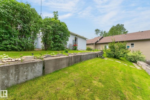 Graded yard with a concrete retaining wall, stone accents, and established landscaping - 351 Smith Crescent, Rural Parkland County, AB - Outdoor