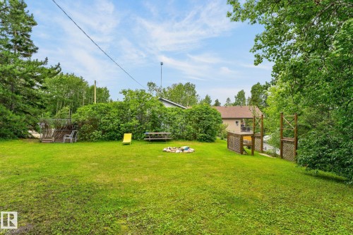 Expansive grass yard with a fire pit, mature trees, and a raised wood deck - 351 Smith Crescent, Rural Parkland County, AB - Outdoor