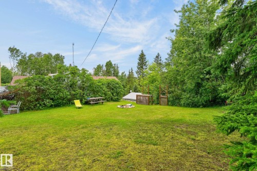 Expansive lawn area with surrounding mature trees and a fire pit - 351 Smith Crescent, Rural Parkland County, AB - Outdoor