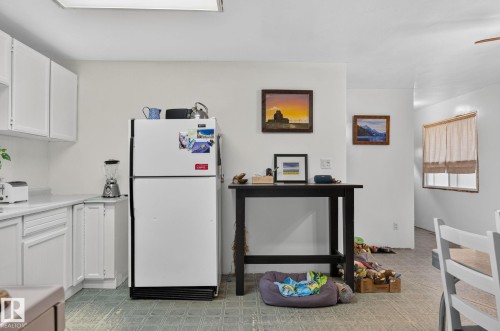 White cabinetry with brushed nickel hardware, white countertops, and a full-size refrigerator - 351 Smith Crescent, Rural Parkland County, AB - Indoor Photo Showing Kitchen