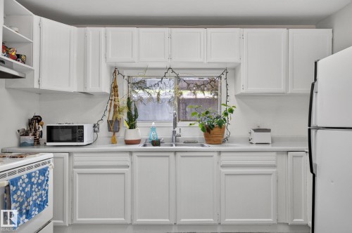 White cabinetry, light-toned countertops, and a stainless steel sink with a window above - 351 Smith Crescent, Rural Parkland County, AB - Indoor Photo Showing Kitchen With Double Sink