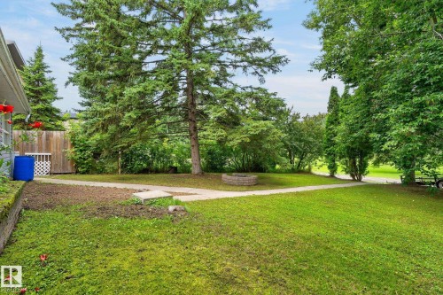 Expansive green lawn with mature trees and a stone-lined fire pit - 351 Smith Crescent, Rural Parkland County, AB - Outdoor